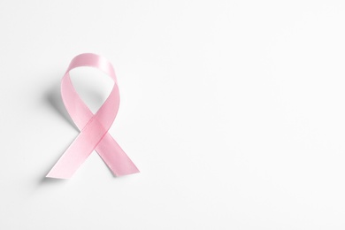 Pink ribbon on white background, top view. Cancer awareness