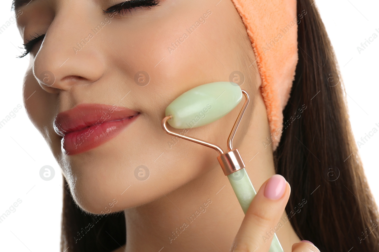 Photo of Woman using natural jade face roller on white background, closeup