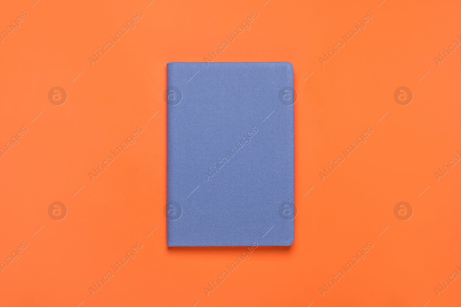 Photo of Closed blue notebook on orange background, top view