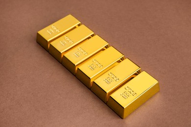 Photo of Many shiny gold bars on brown background