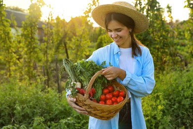 Photo of Woman with basket of different fresh ripe vegetables on farm