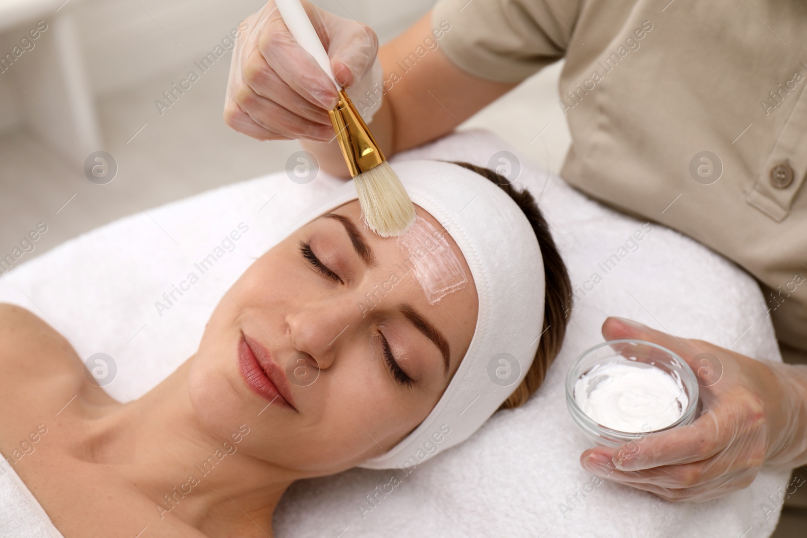 Photo of Young woman during face peeling procedure in salon