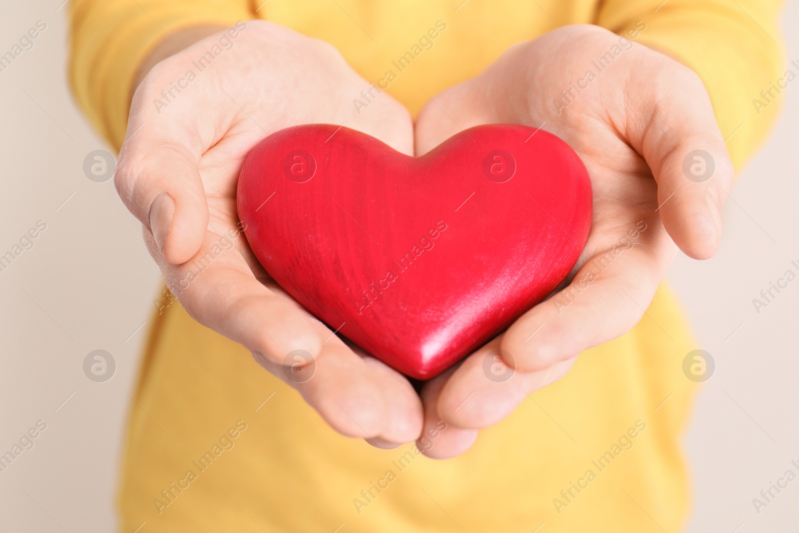 Photo of Man holding decorative heart in hands on color background, closeup