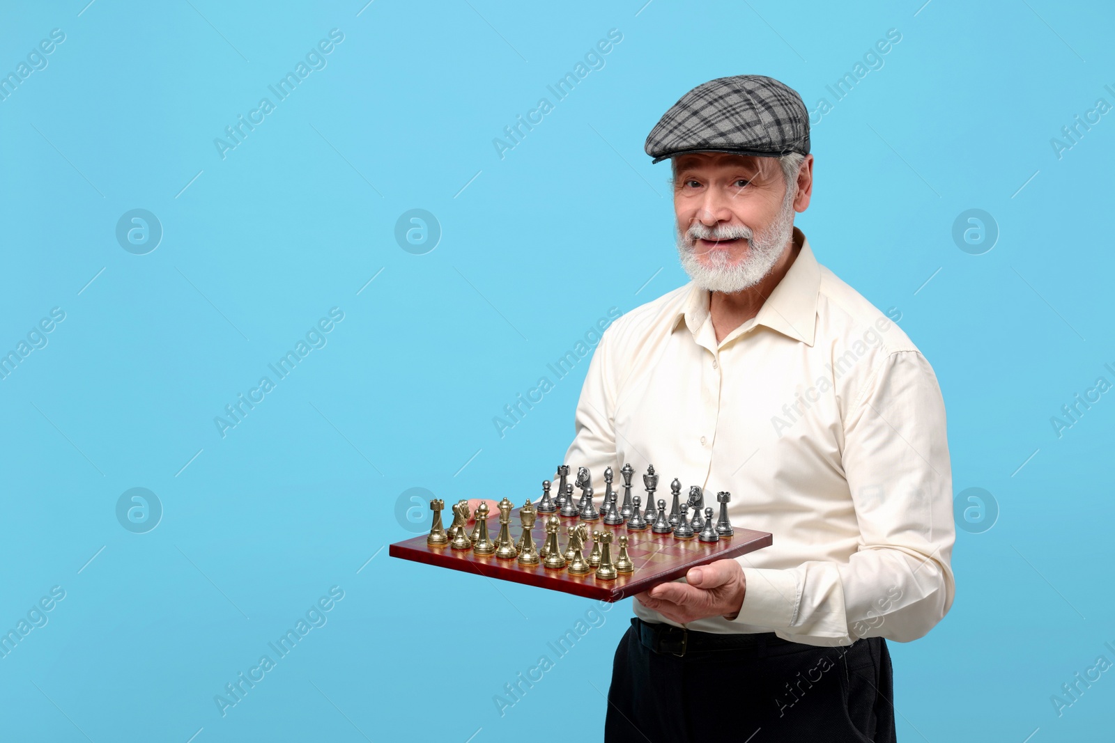 Photo of Man with chessboard and game pieces on light blue background. Space for text