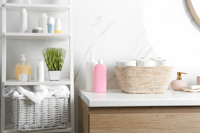 Wicker basket with toilet paper rolls on countertop in bathroom