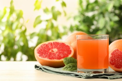 Glass of delicious grapefruit juice on white table against blurred background, space for text