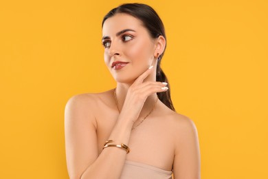 Beautiful woman with elegant jewelry on orange background