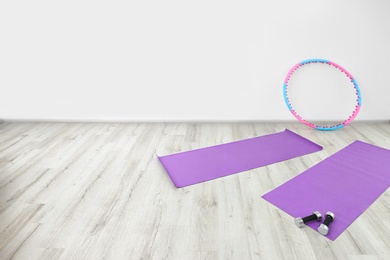 Photo of Hula hoop, yoga mats and dumbbells in physiotherapy gym
