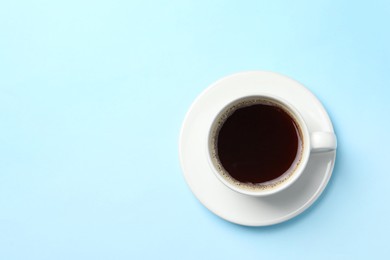 Cup of aromatic coffee on light blue background, top view. Space for text