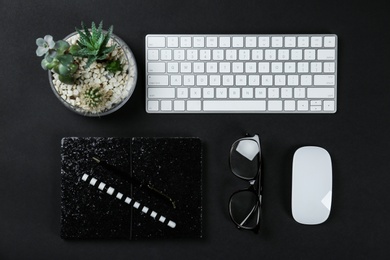 Photo of Flat lay composition with computer keyboard and notebook on black background. Graphic designer's workplace