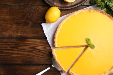 Photo of Delicious homemade lemon pie on wooden table, flat lay. Space for text