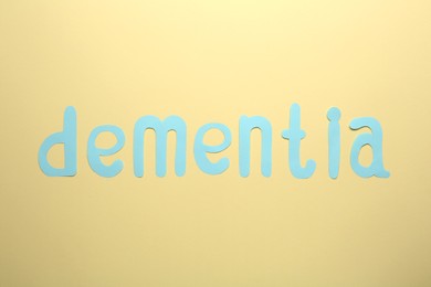 Photo of Word Dementia made of paper letters on beige background, flat lay