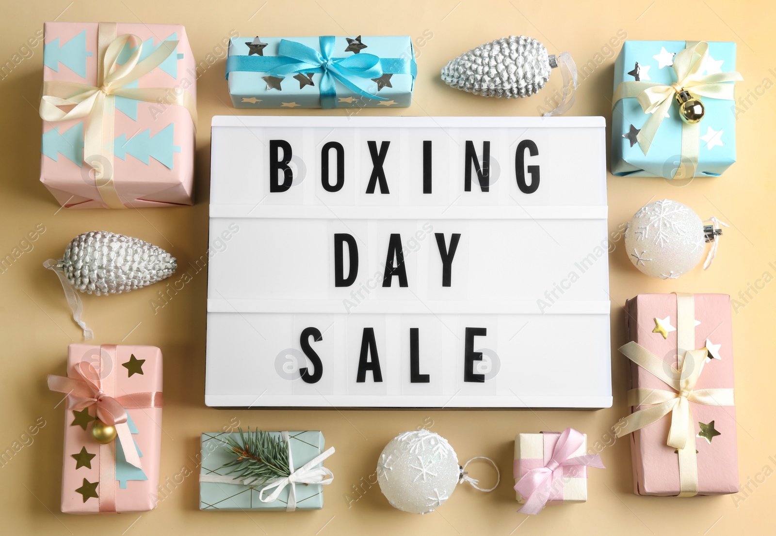 Photo of Lightbox with phrase BOXING DAY SALE and Christmas decorations on beige background, flat lay