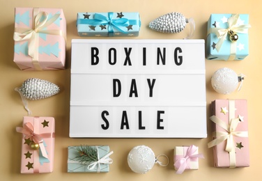 Lightbox with phrase BOXING DAY SALE and Christmas decorations on beige background, flat lay