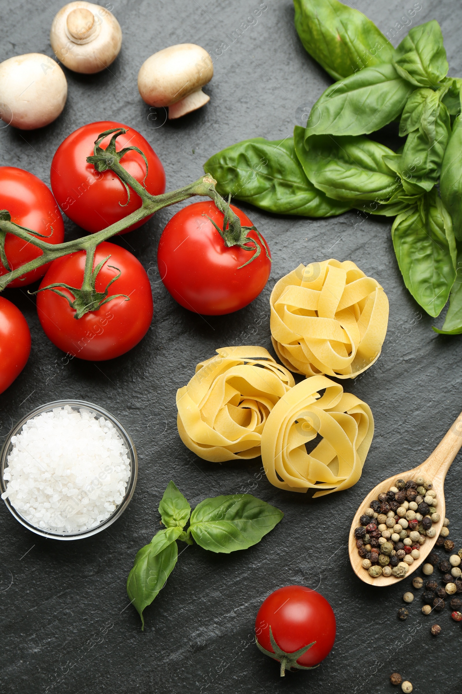 Photo of Pasta, spices and products on dark textured table, flat lay