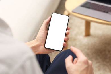 Photo of Man using smartphone with blank screen indoors, closeup. Mockup for design