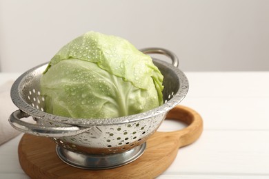 Photo of Wet cabbage in colander on white table, closeup