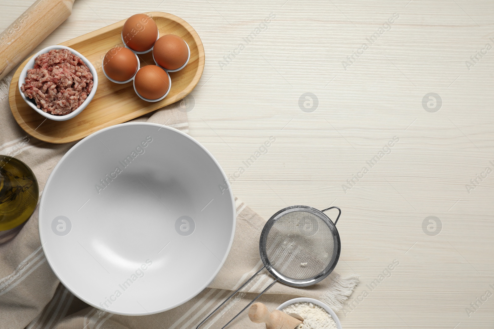 Photo of Bowl and different products on white wooden table, flat lay. Space for text