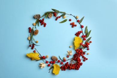 Photo of Dried flowers, leaves and berries arranged in shape of wreath on light blue background, flat lay with space for text. Autumnal aesthetic