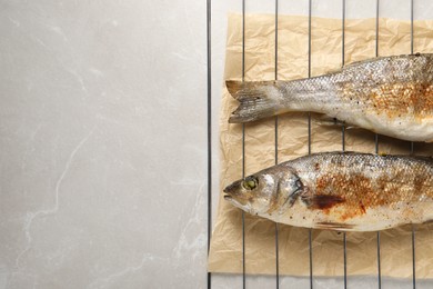 Photo of Baked fish on light marble table, top view. Space for text