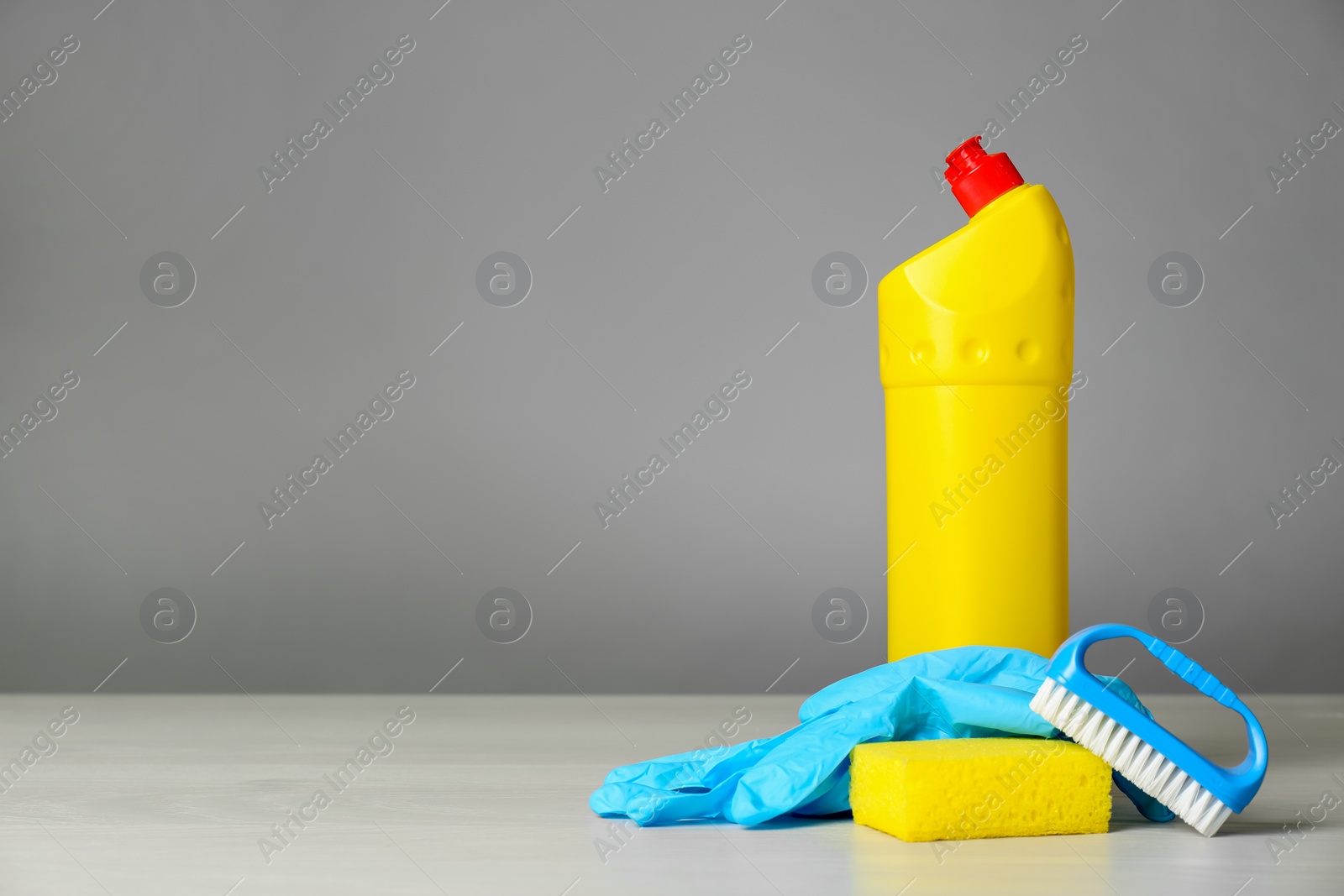 Photo of Bottle of cleaning product and supplies on light table. Space for text