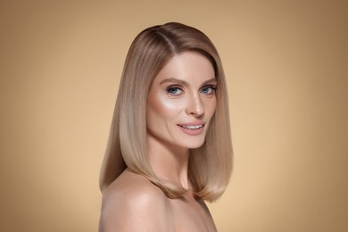 Image of Portrait of attractive woman with blonde hair on dark beige background