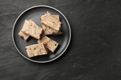 Photo of Tasty chocolate halva on black table, top view. Space for text