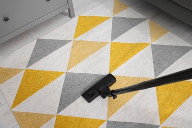 Photo of Hoovering carpet with vacuum cleaner indoors, above view