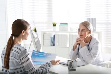 Photo of Doctor consulting patient at desk in clinic