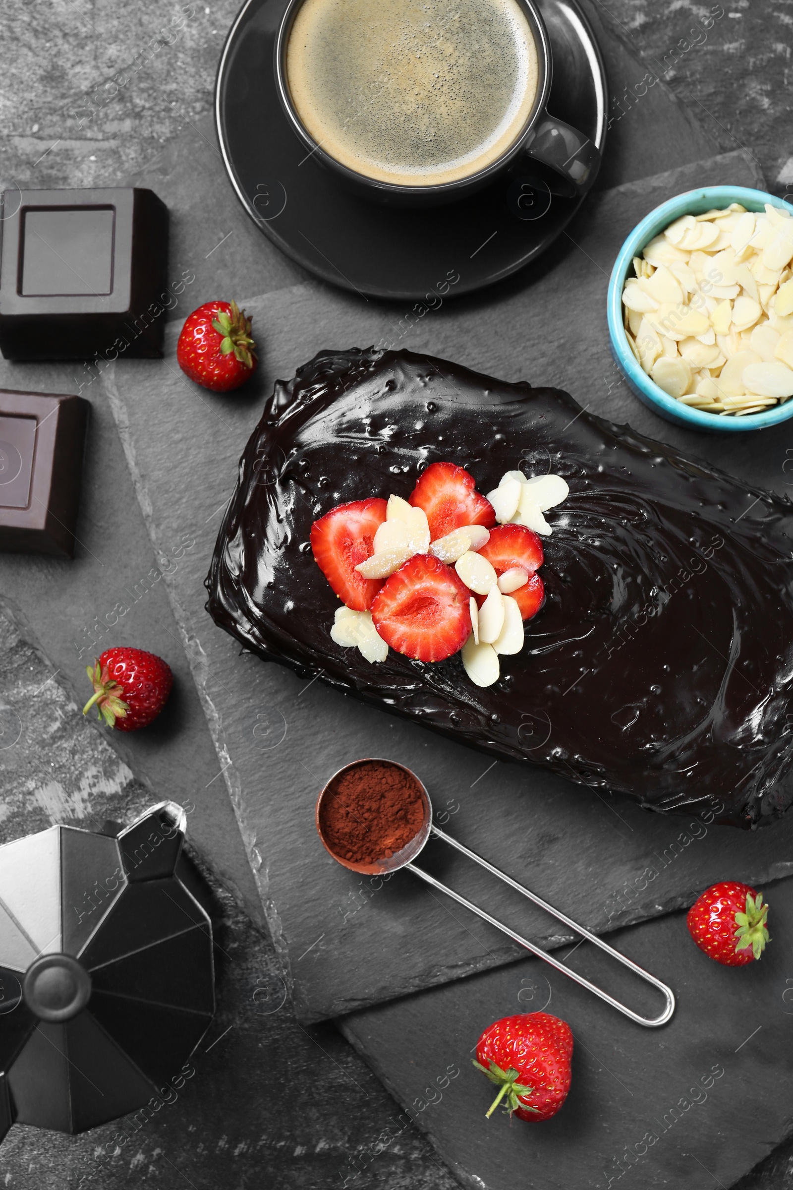 Photo of Delicious chocolate sponge cake, coffee and ingredients on black table, flat lay