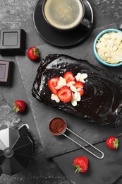 Delicious chocolate sponge cake, coffee and ingredients on black table, flat lay