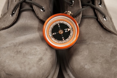 Photo of Small compass and hiking boots, closeup. Camping items
