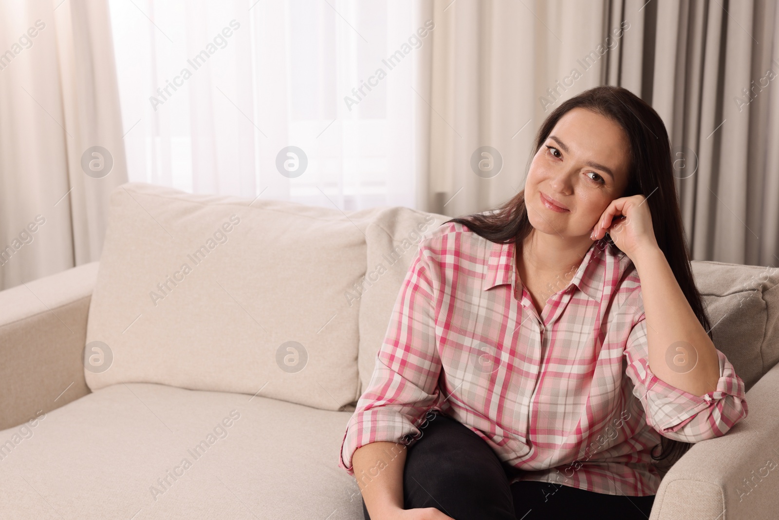 Photo of Beautiful overweight woman sitting on sofa at home