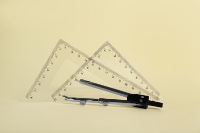Photo of Triangle rulers and compass on light yellow background