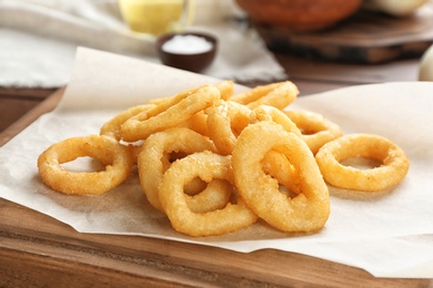 Tasty fried onion rings on wooden table