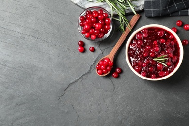 Flat lay composition with cranberry sauce and fresh berries on dark grey table. Space for text