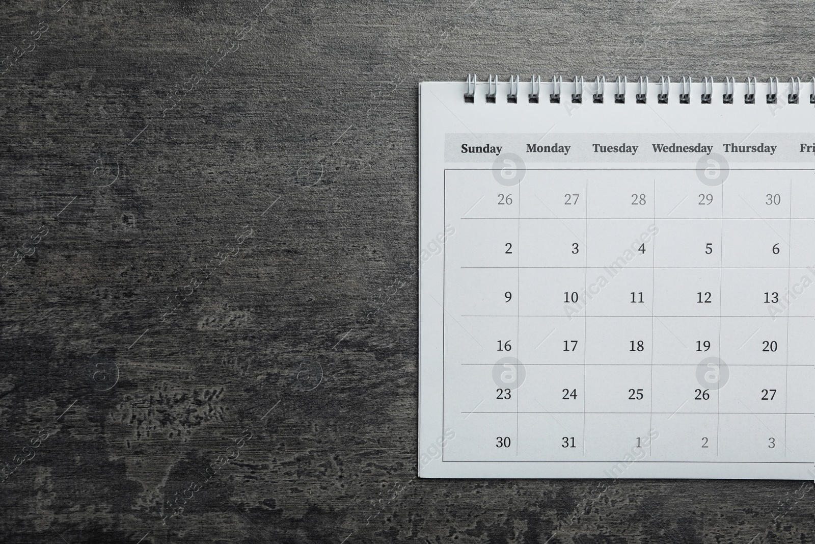 Photo of Paper calendar on grey stone background, top view. Space for text