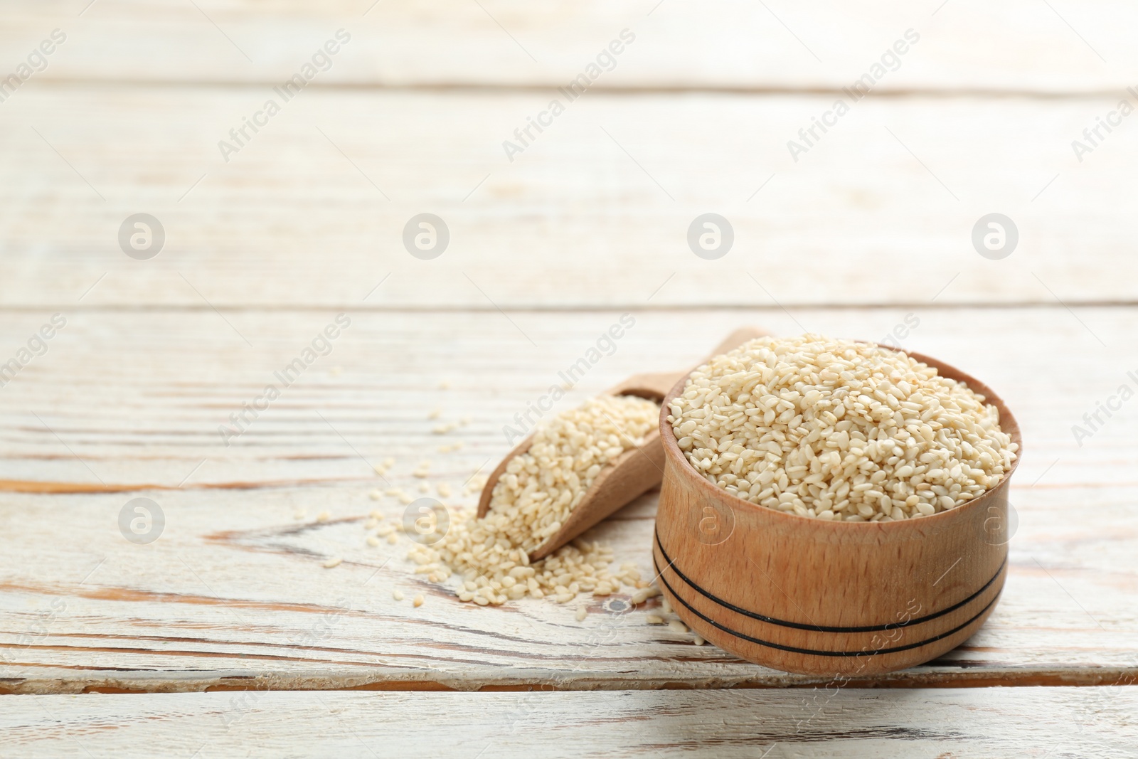 Photo of White sesame seeds on wooden table. Space for text