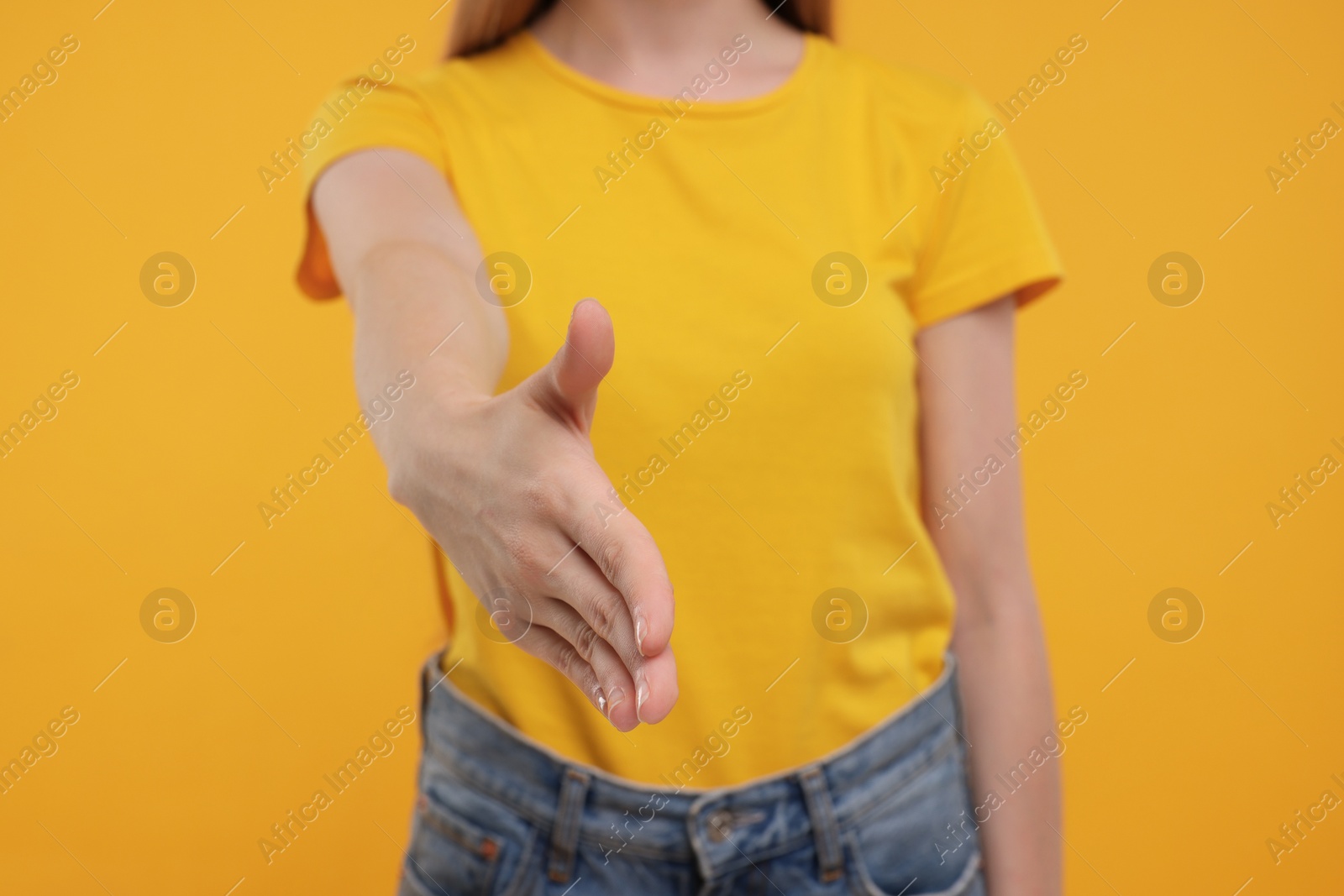 Photo of Woman welcoming and offering handshake on yellow background, closeup