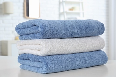 Photo of Stack of fresh towels on table in bathroom, closeup