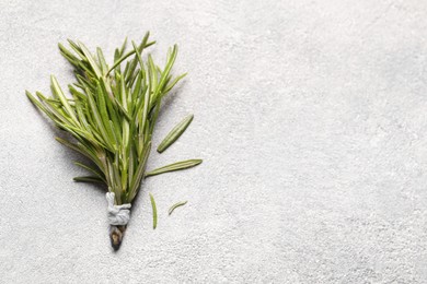 Photo of Bunch of fresh rosemary on light textured table, top view and space for text