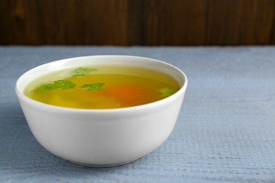 Delicious chicken bouillon with parsley on grey wooden table, closeup. Space for text