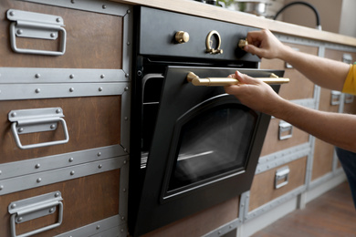 Man using modern oven in kitchen, closeup