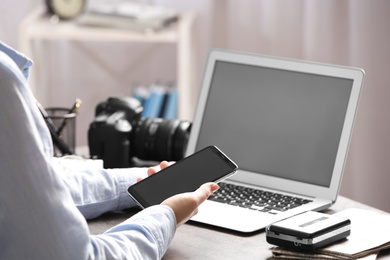 Journalist with smartphone working at table in office, closeup