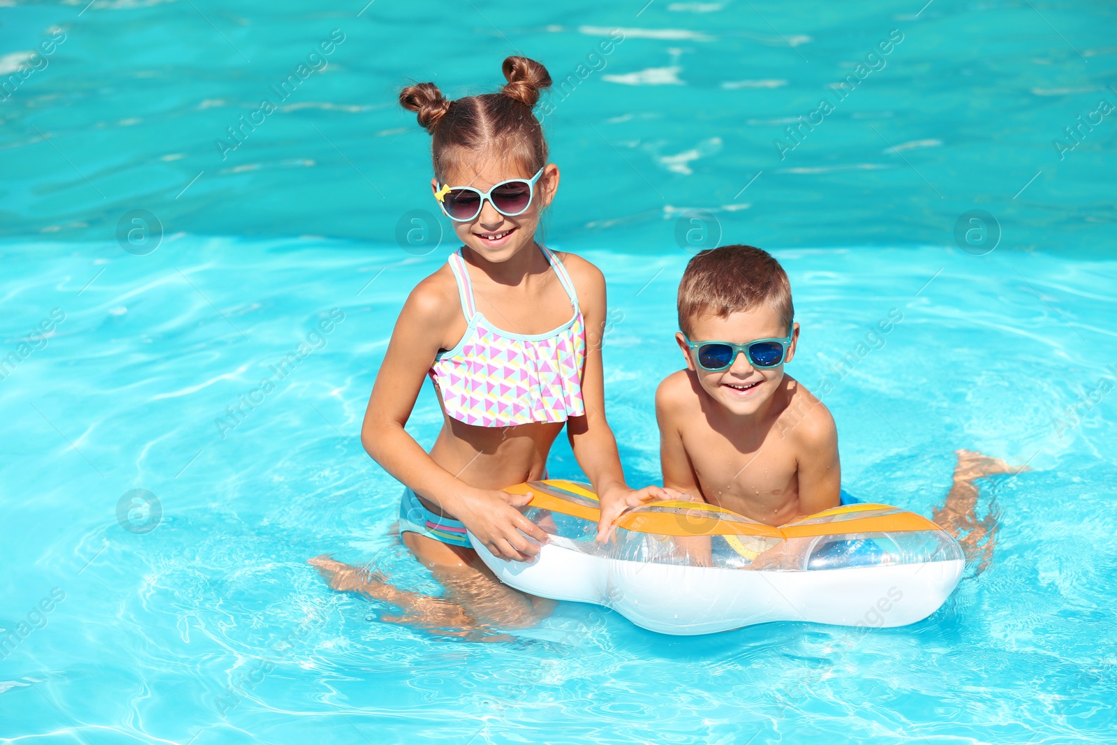 Photo of Cute little children with inflatable ring in swimming pool