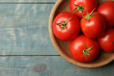 Photo of Ripe tomatoes in bowl on blue wooden table, top view. Space for text
