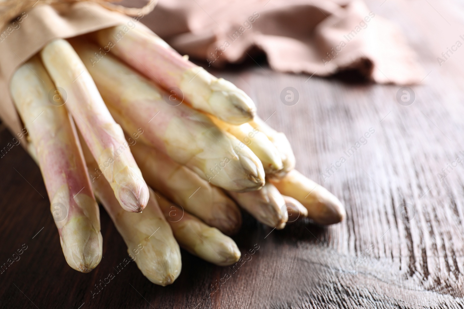 Photo of Bunch of fresh white asparagus on wooden table, closeup