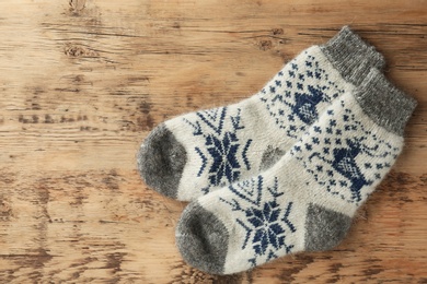 Photo of Knitted socks on wooden background, flat lay