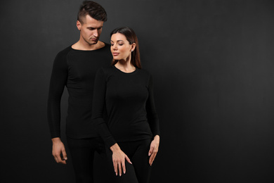 Photo of Couple wearing thermal underwear on black background. Space for text