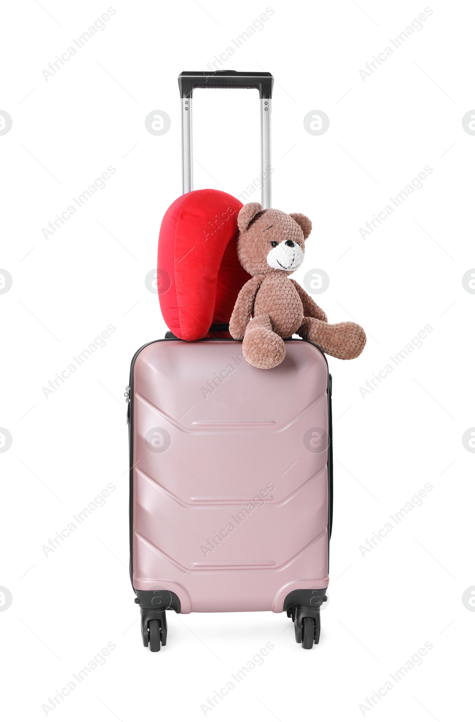 Photo of Red travel pillow and toy bear on suitcase against white background